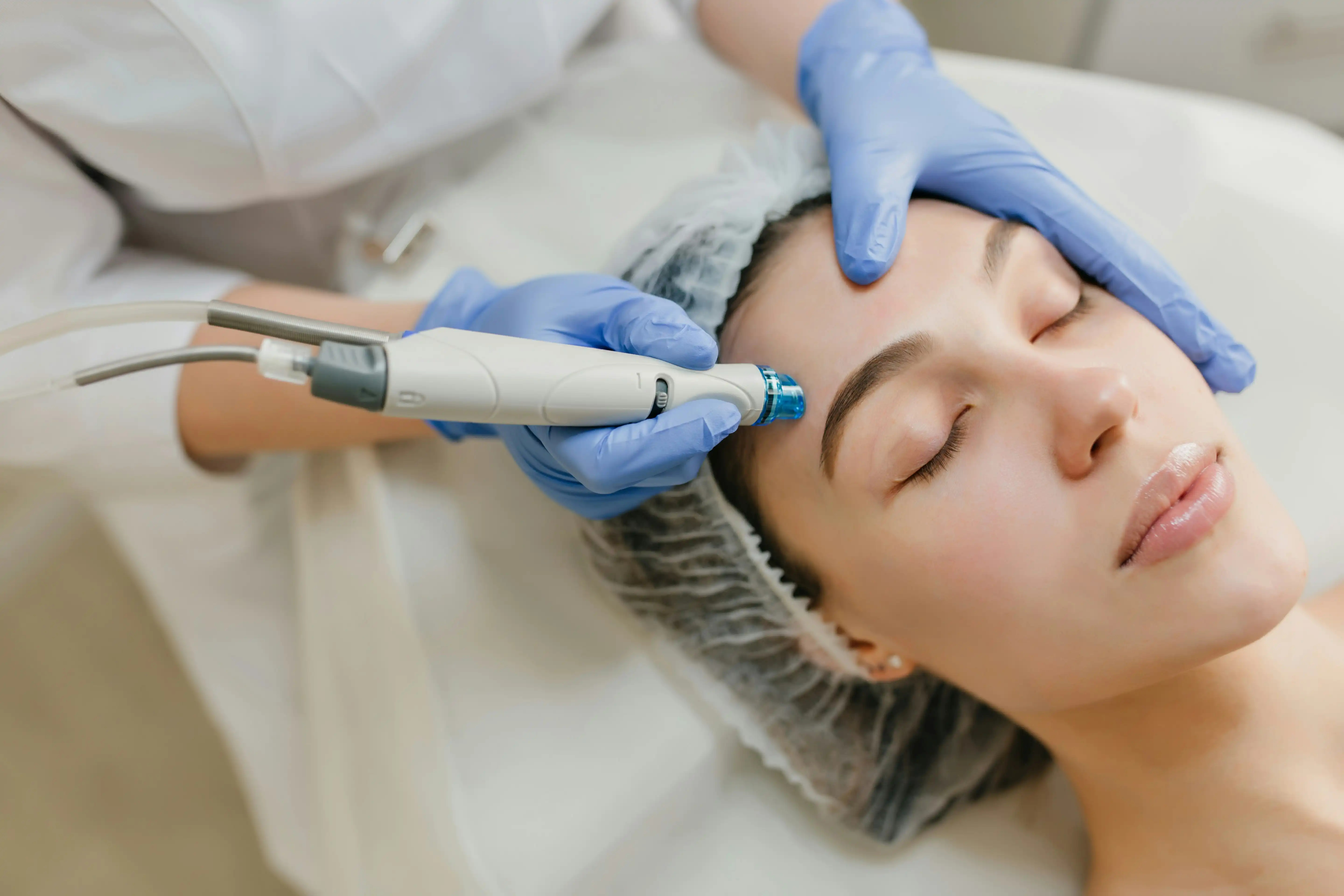 Professional facial treatment with therapist using skincare device on forehead for rejuvenation.