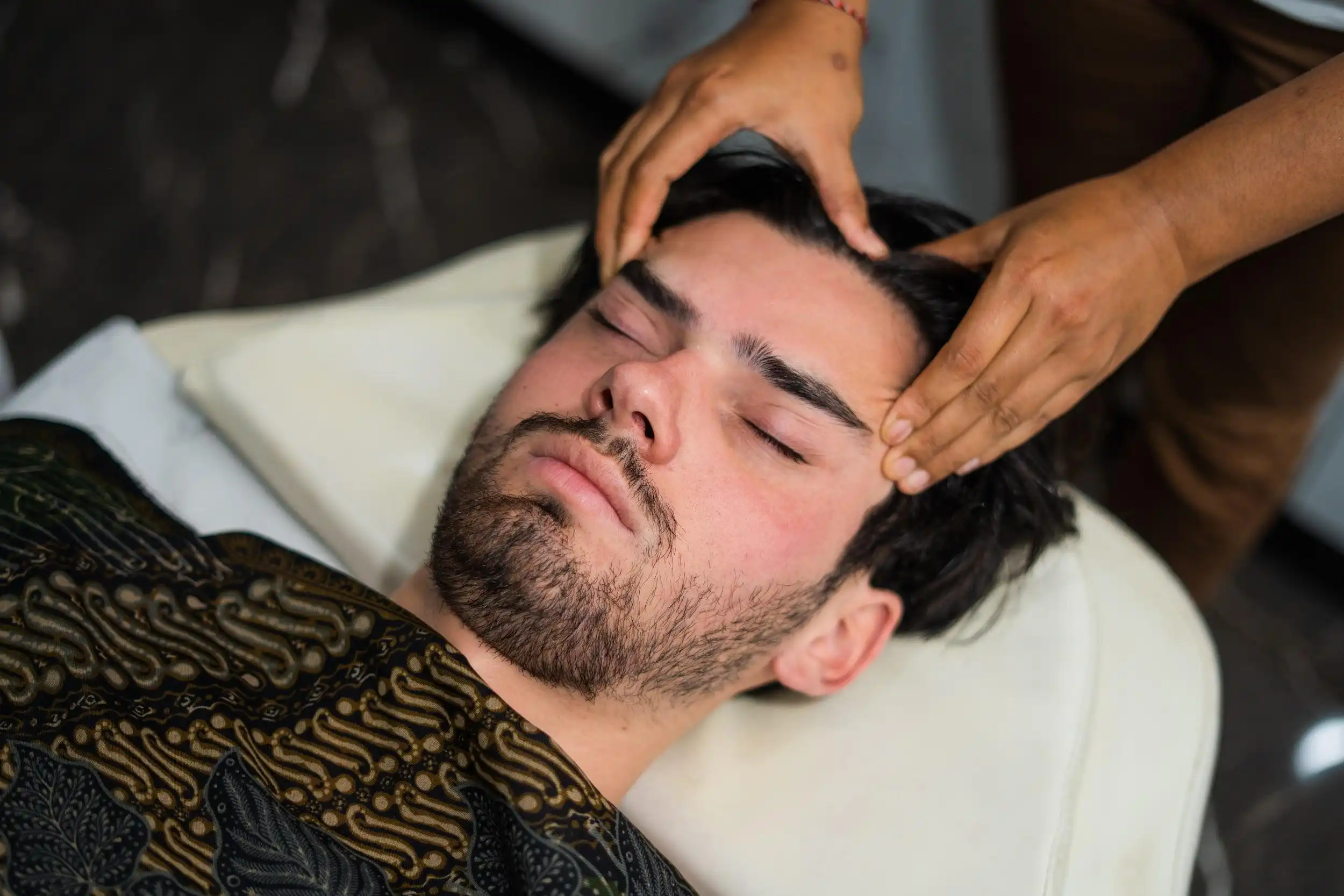 Spa head massage with therapist’s hands gently pressing forehead and scalp for relaxation.