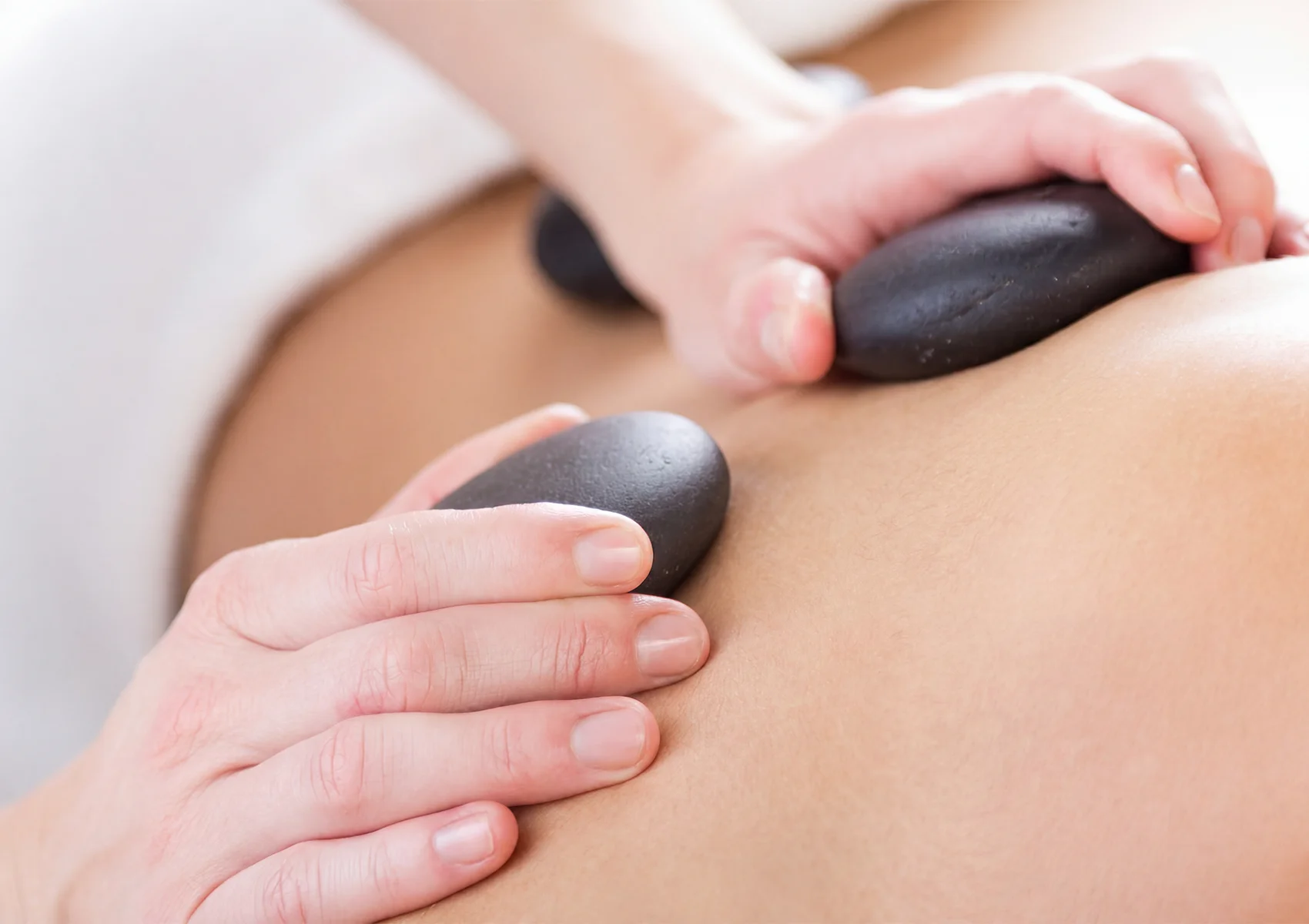 Hot stone massage treatment for muscle relaxation at a wellness spa in Ubud, Bali.
