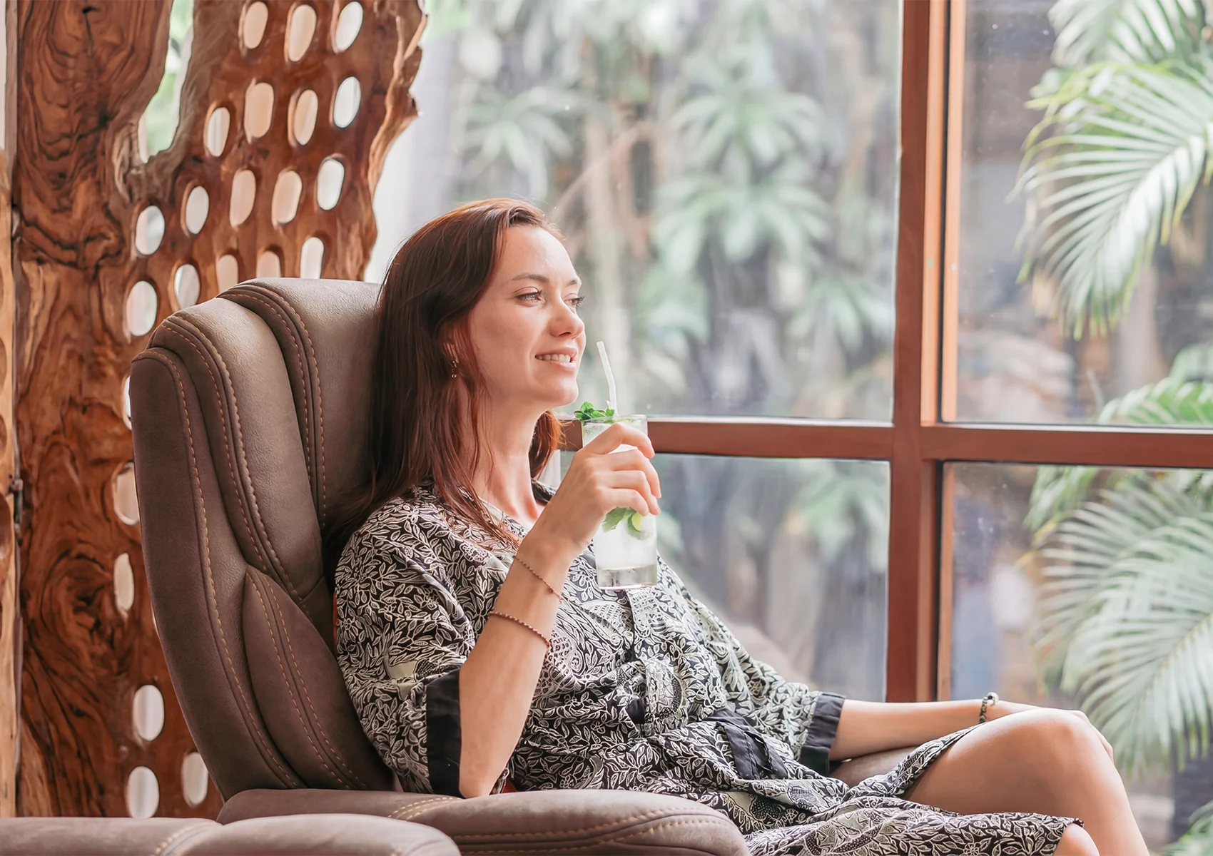 Woman relaxing in a spa lounge in Ubud with a refreshing drink after a wellness massage treatment.
