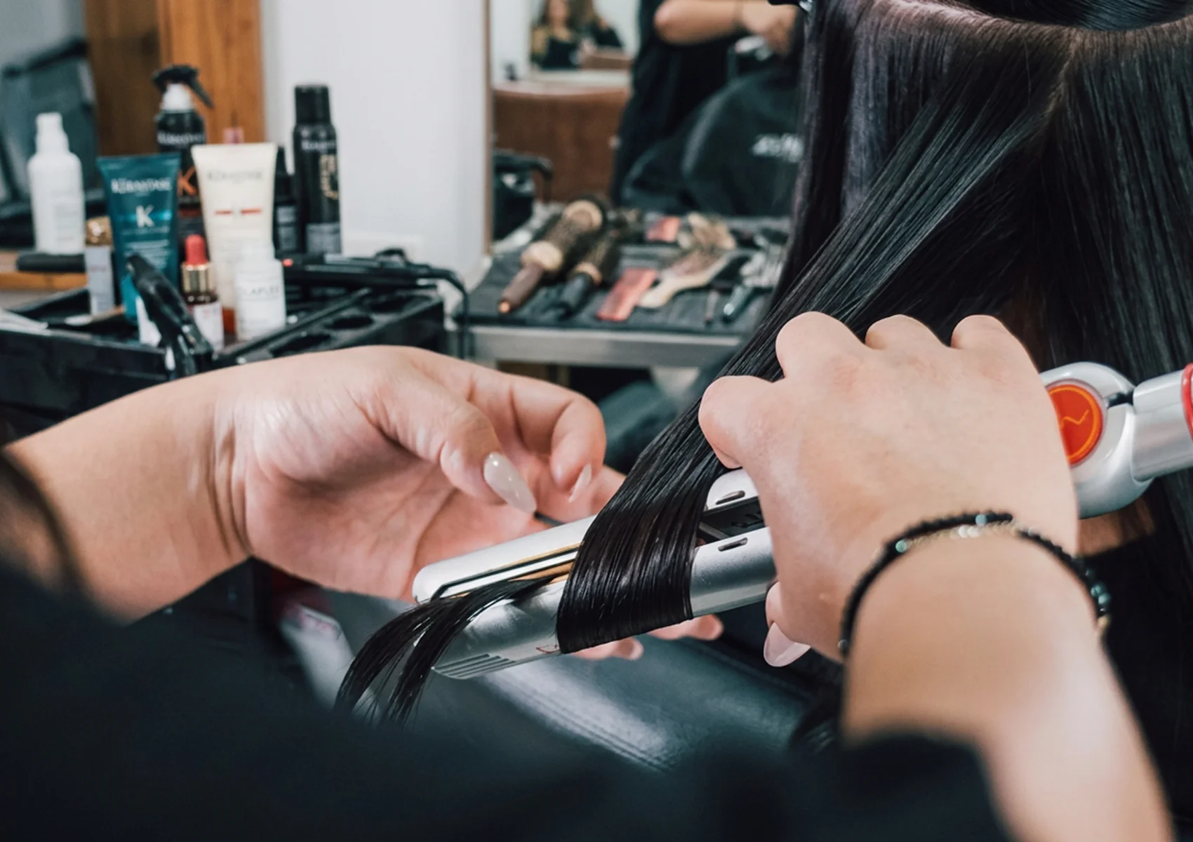 Professional hair styling treatment in a Bali beauty salon with a stylist using a curling iron to smooth and style long, healthy hair for a sleek, polished finish